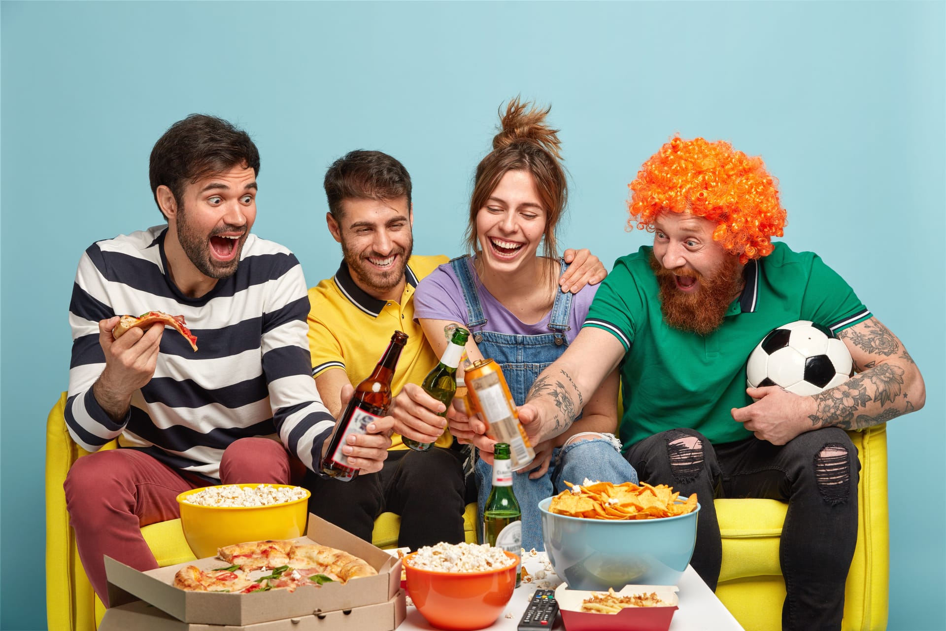 Happy friends sitting on a couch and enjoying food and drinks deliveries.