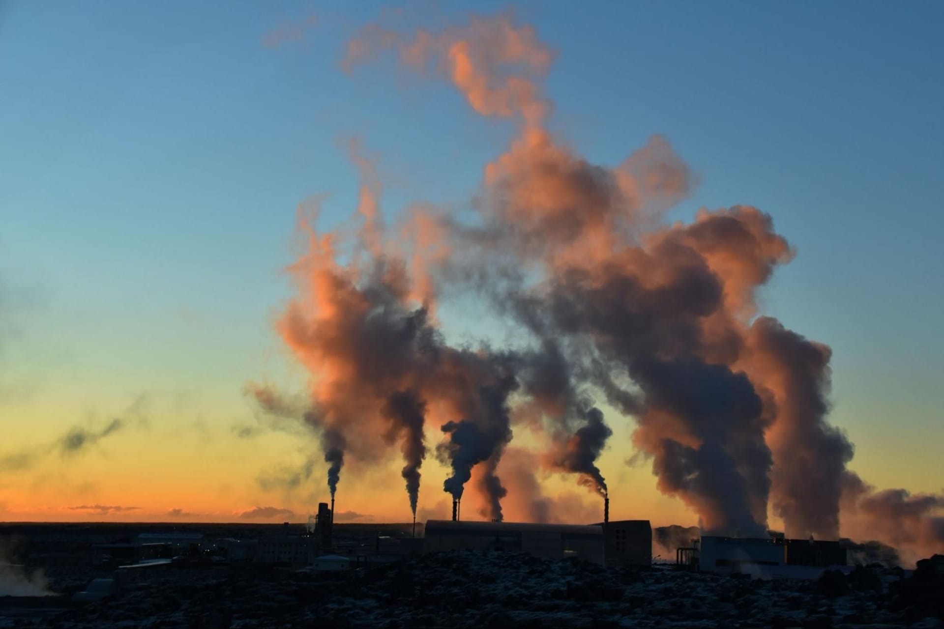 Smoking factories during a sunset in the horizon
