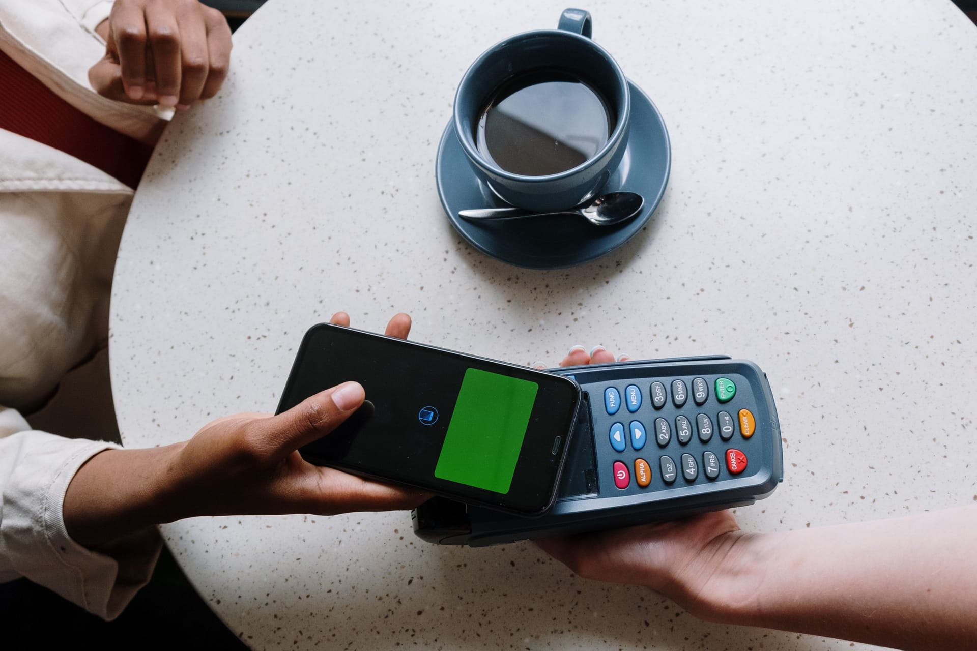A woman who is paying for her coffee with her smartphone.