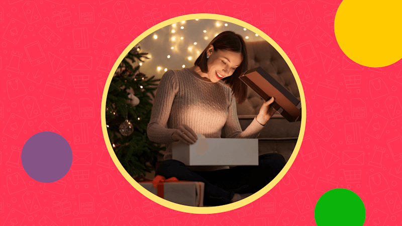 Brunette women opening a present next to the Christmas tree on a red background