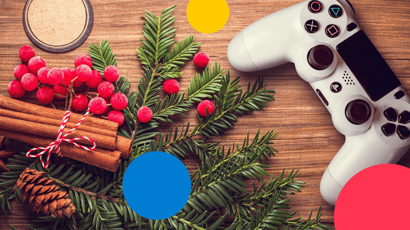 Ein Holztisch, auf dem ein Gamecontroller für die PlayStation 4 liegt, sowie Weihnachtsdekoration in Form von Tannenzweigen, Tannenzapfen, roten Beeren und Zimtstangen.