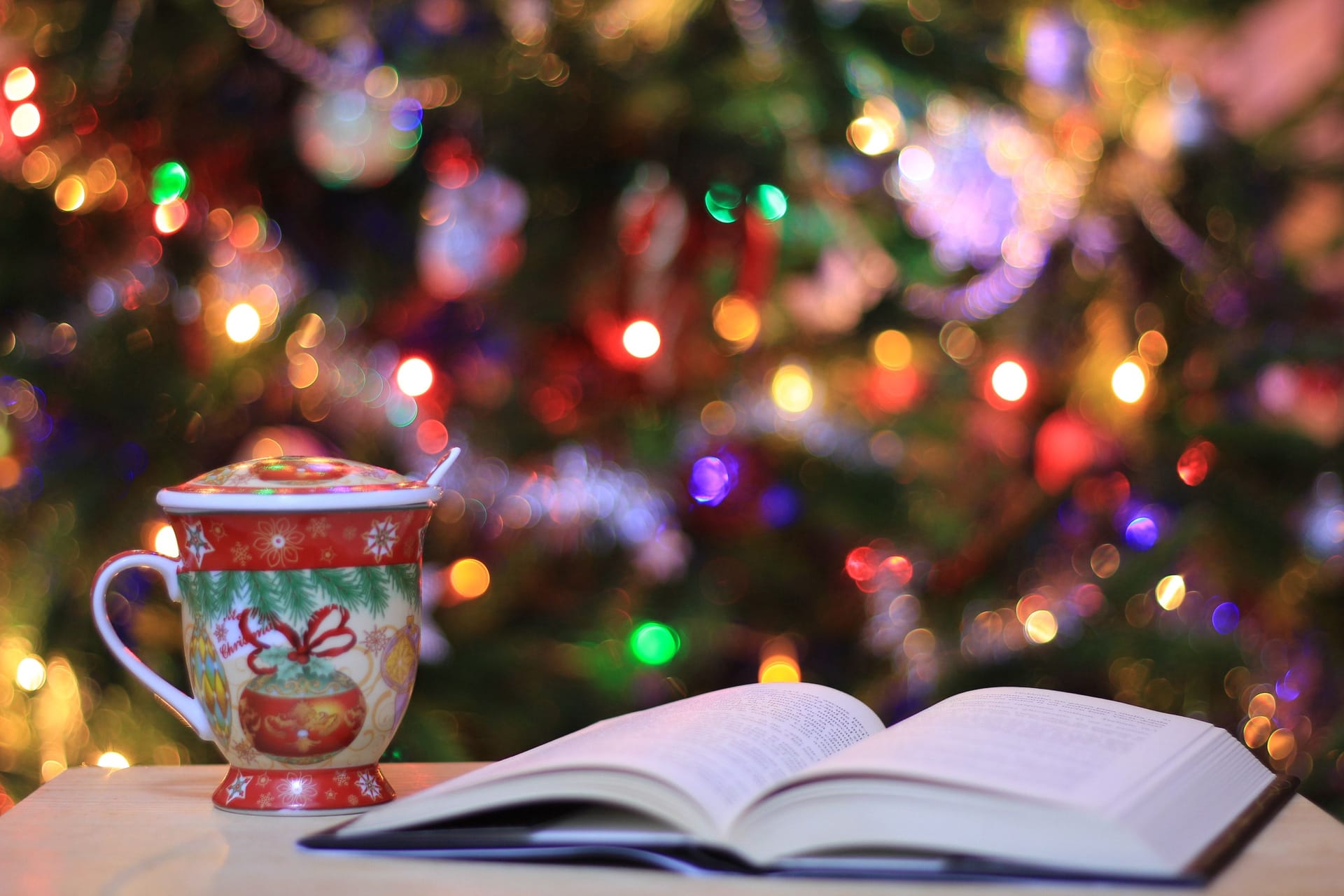 A book open and a mug in front of a Christmas tree