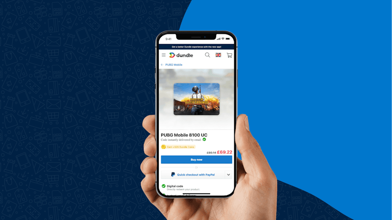 A hand holding a smartphone with the dundle webpage open on the PUBG Mobile 8100 UC product page showing the price of £69.22 and “Buy now” button.