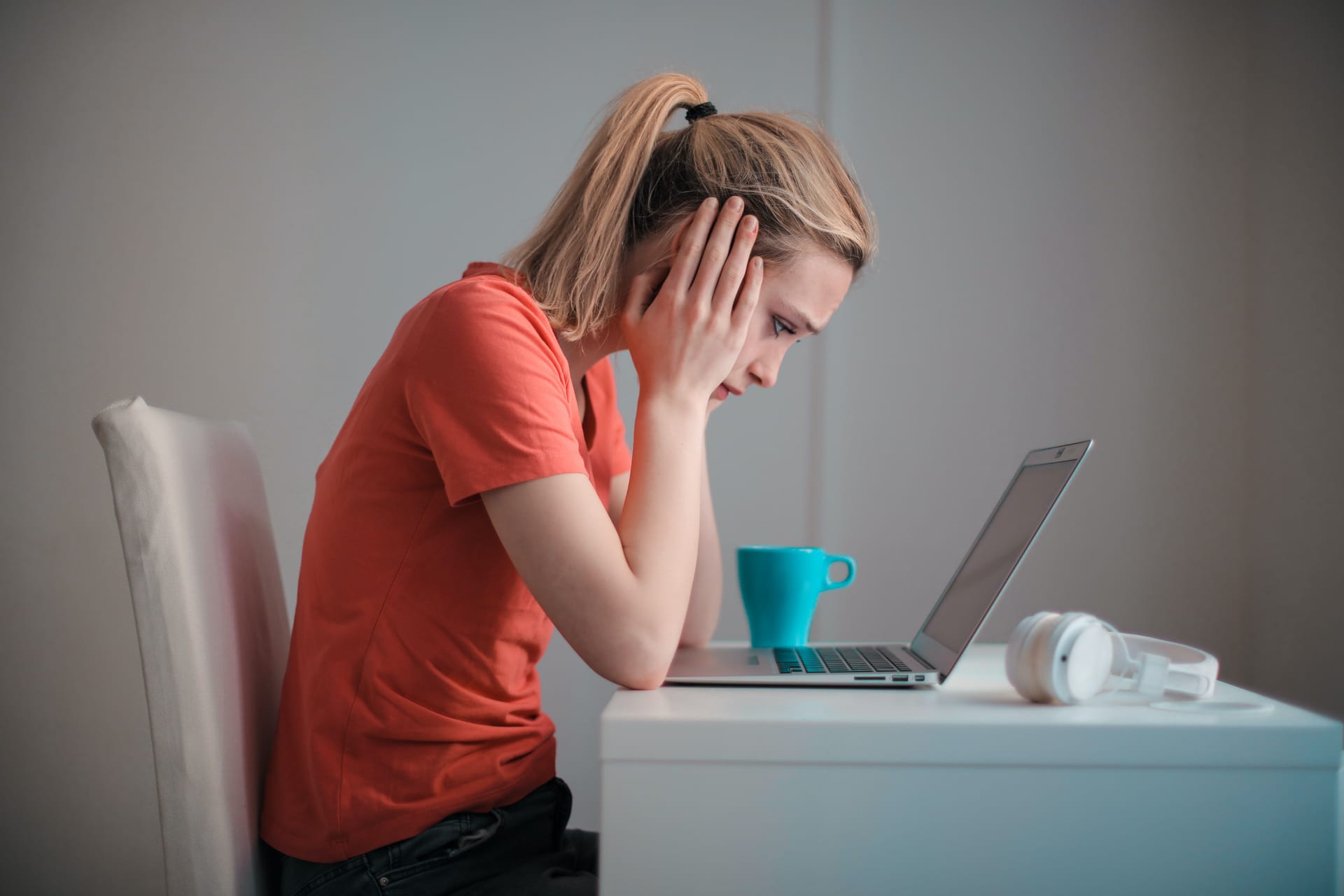 A woman looking worried at a screen because she has been scammed online