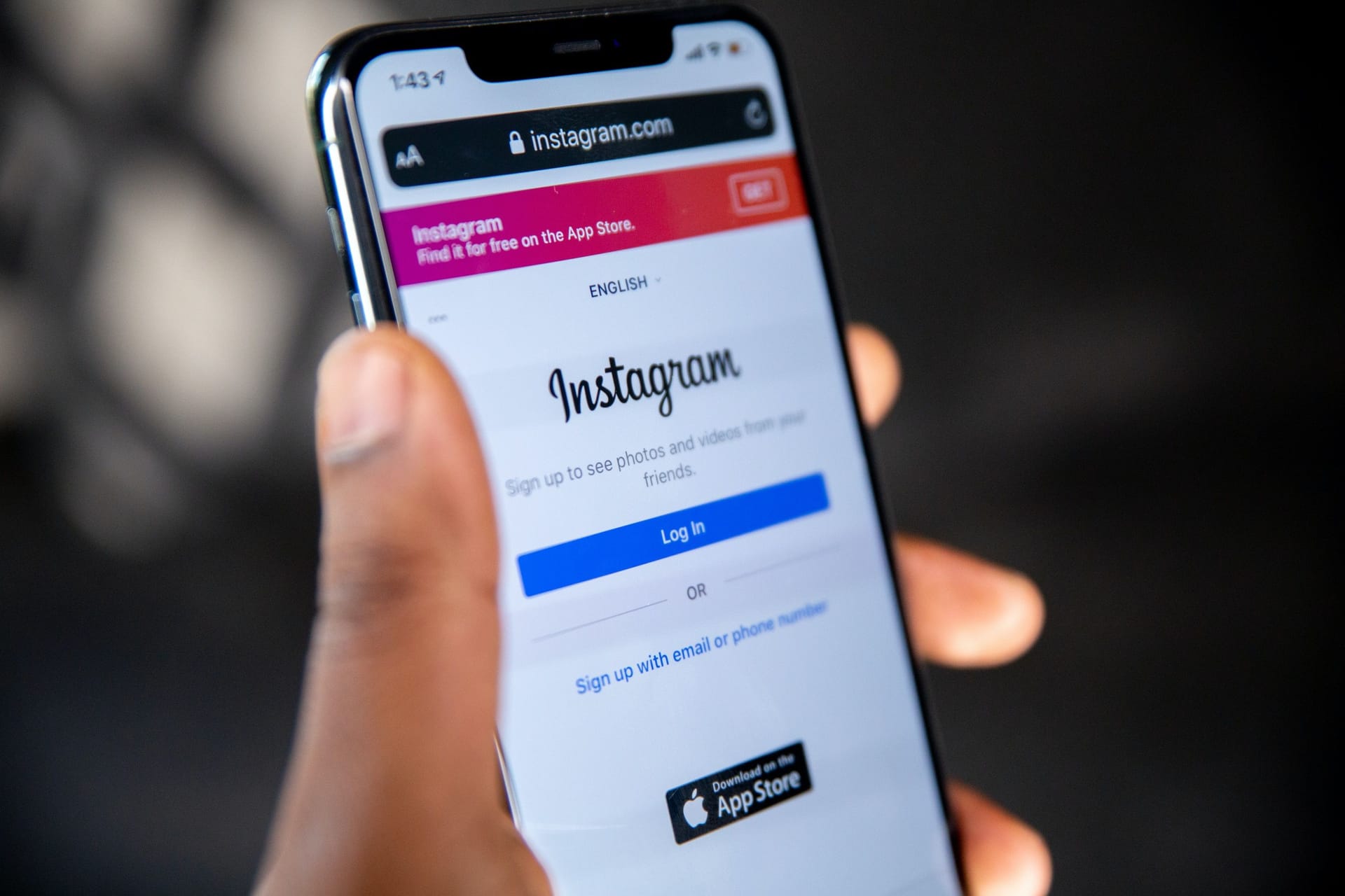 Someone holding a phone from up close. The screen shows the login screen for the Instagram app.
