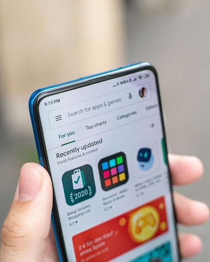 L'application Google Play Store ouverte sur un téléphone Android tenu par une main.