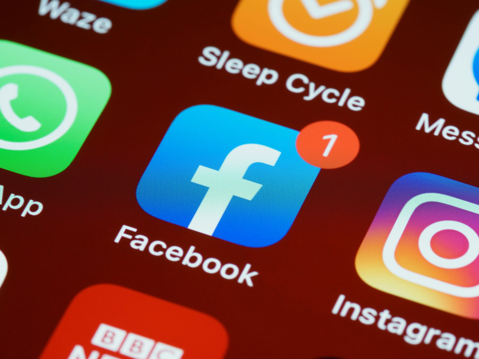 The facebook logo on a phone. There are other apps like Whatsapp, Instagram and Sleep Cycle around it.