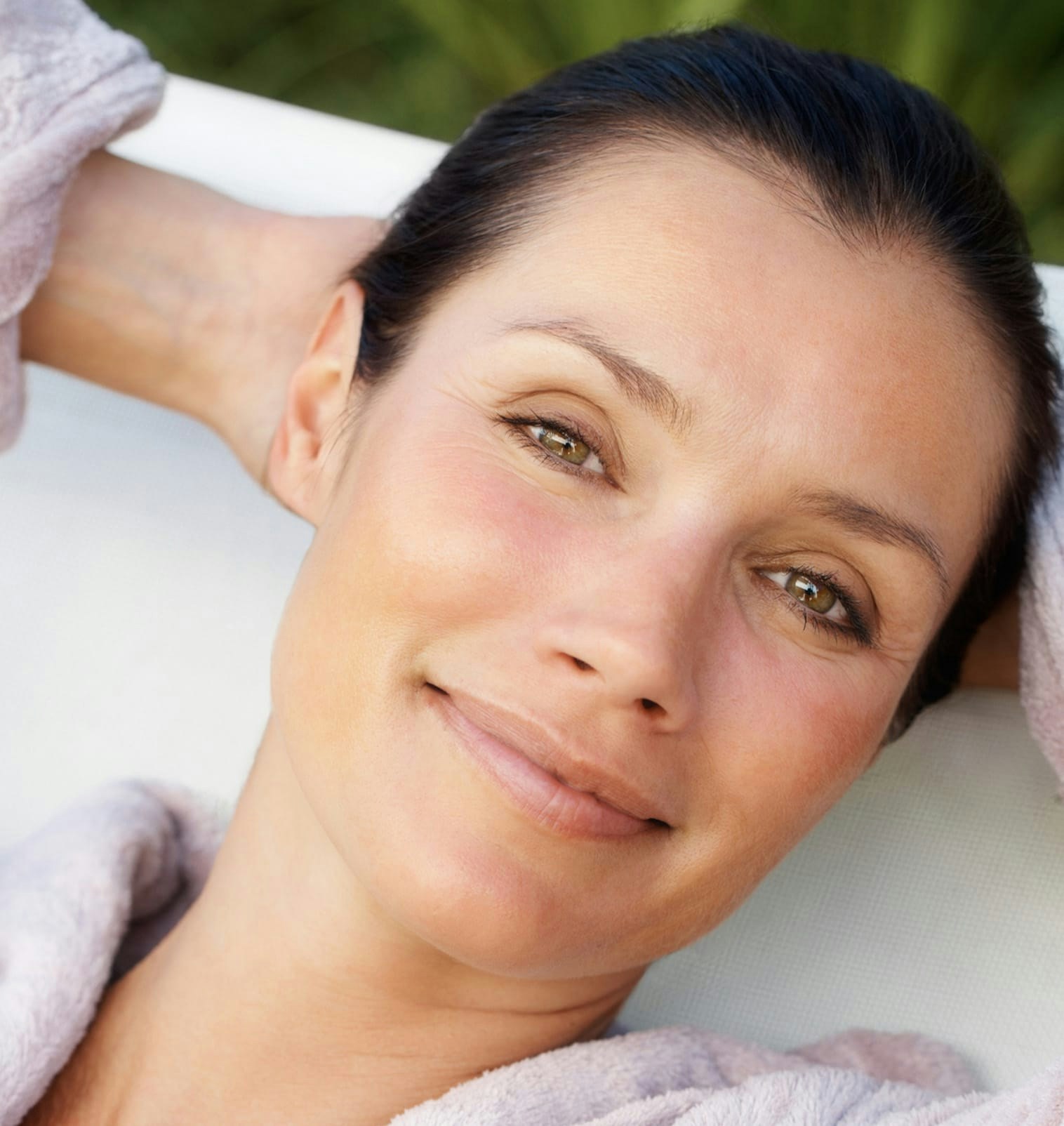 close up of smiling woman with hands behind head