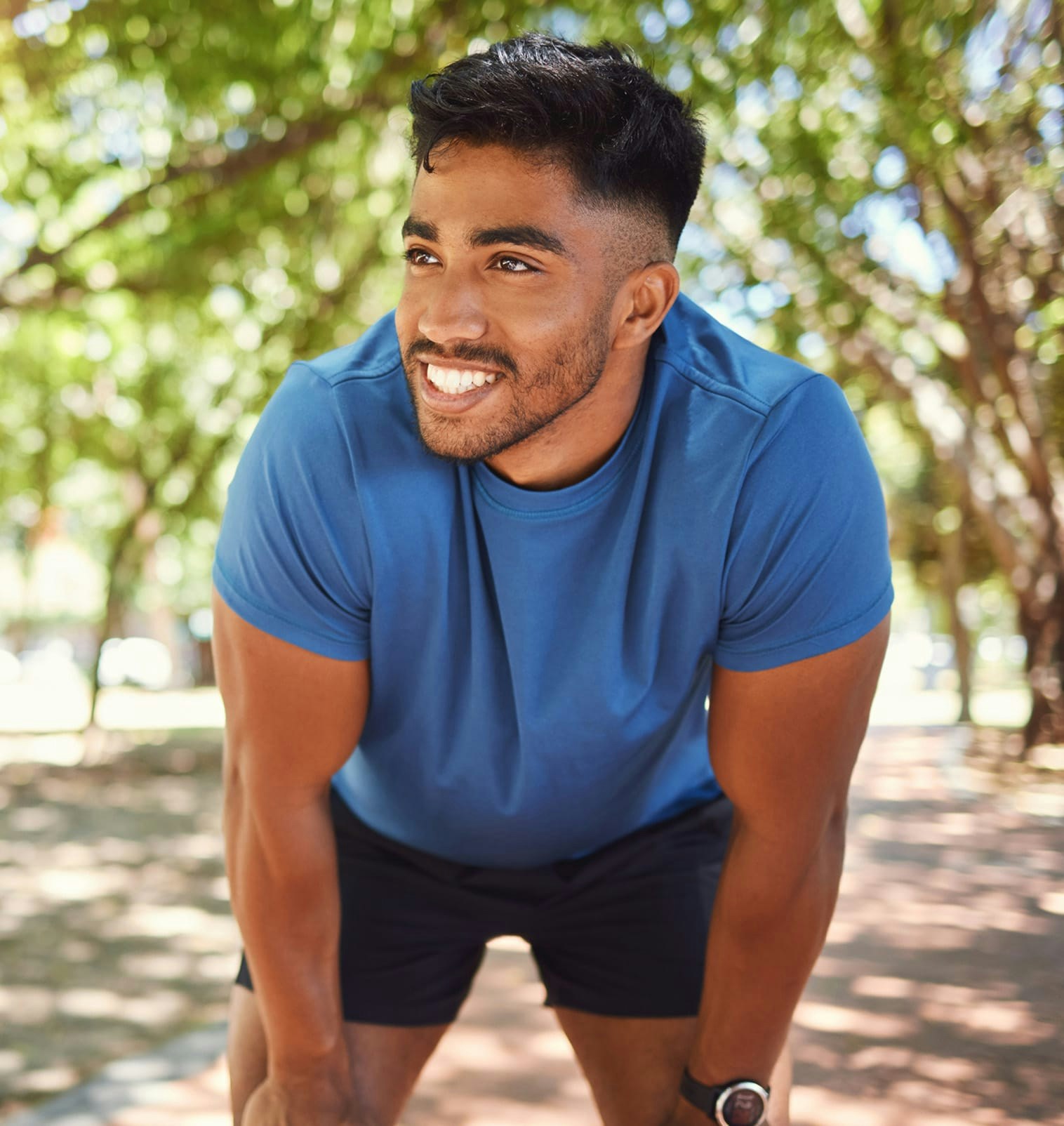 smiling man in athletic wear bent over looking right