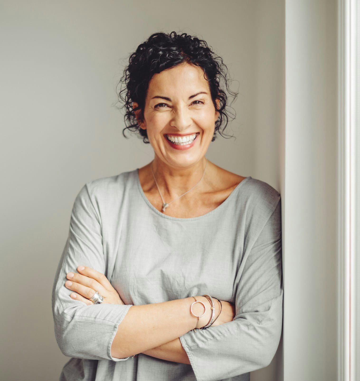 smiling woman with arms crossed in doorway