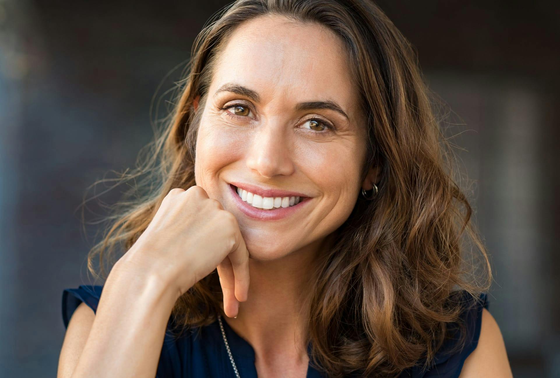 Woman smiling at camera with hand on chin