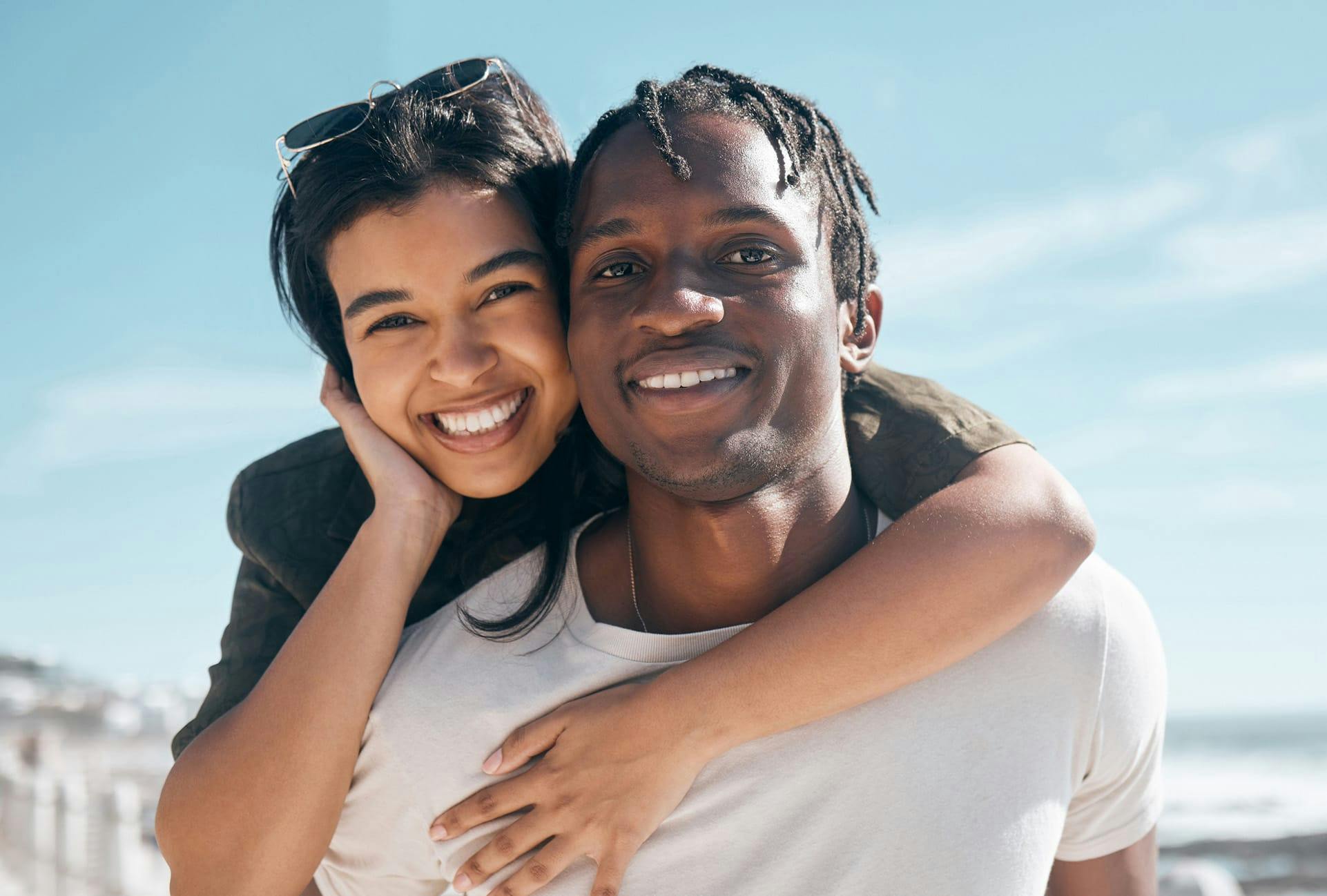 smiling couple with woman hugging man from behind