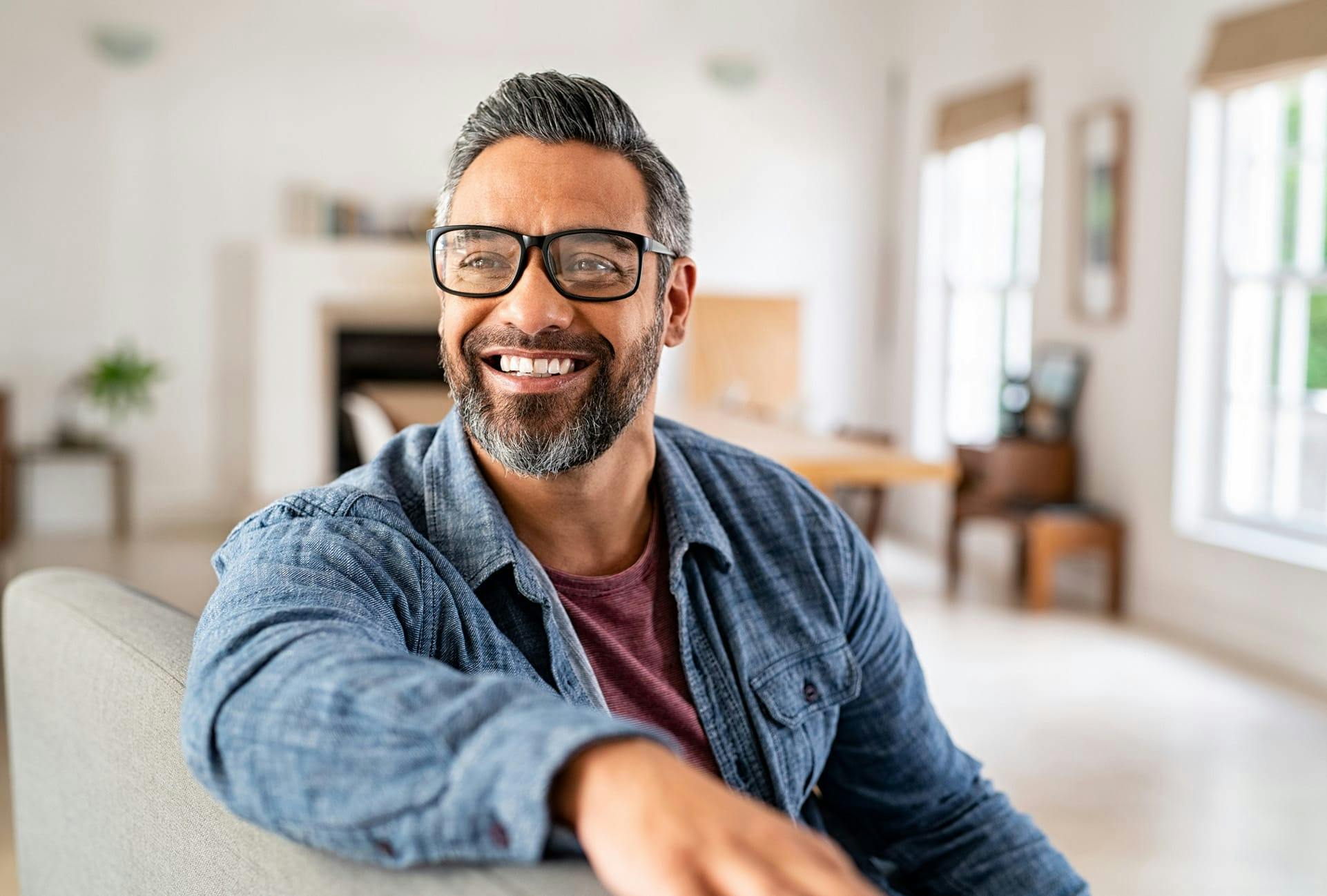 smiling man wearing glasses with arm on back of chair