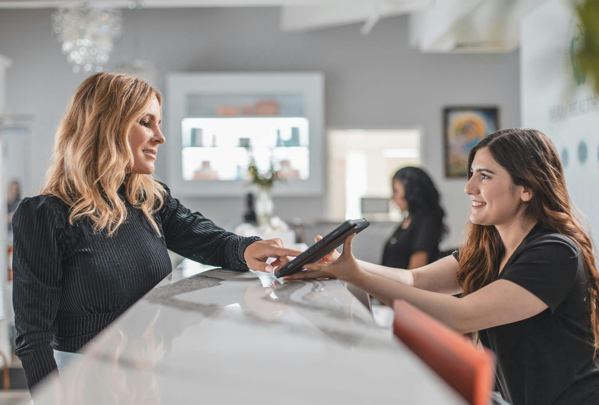 smiling customer service representative holds POS device for smiling customer