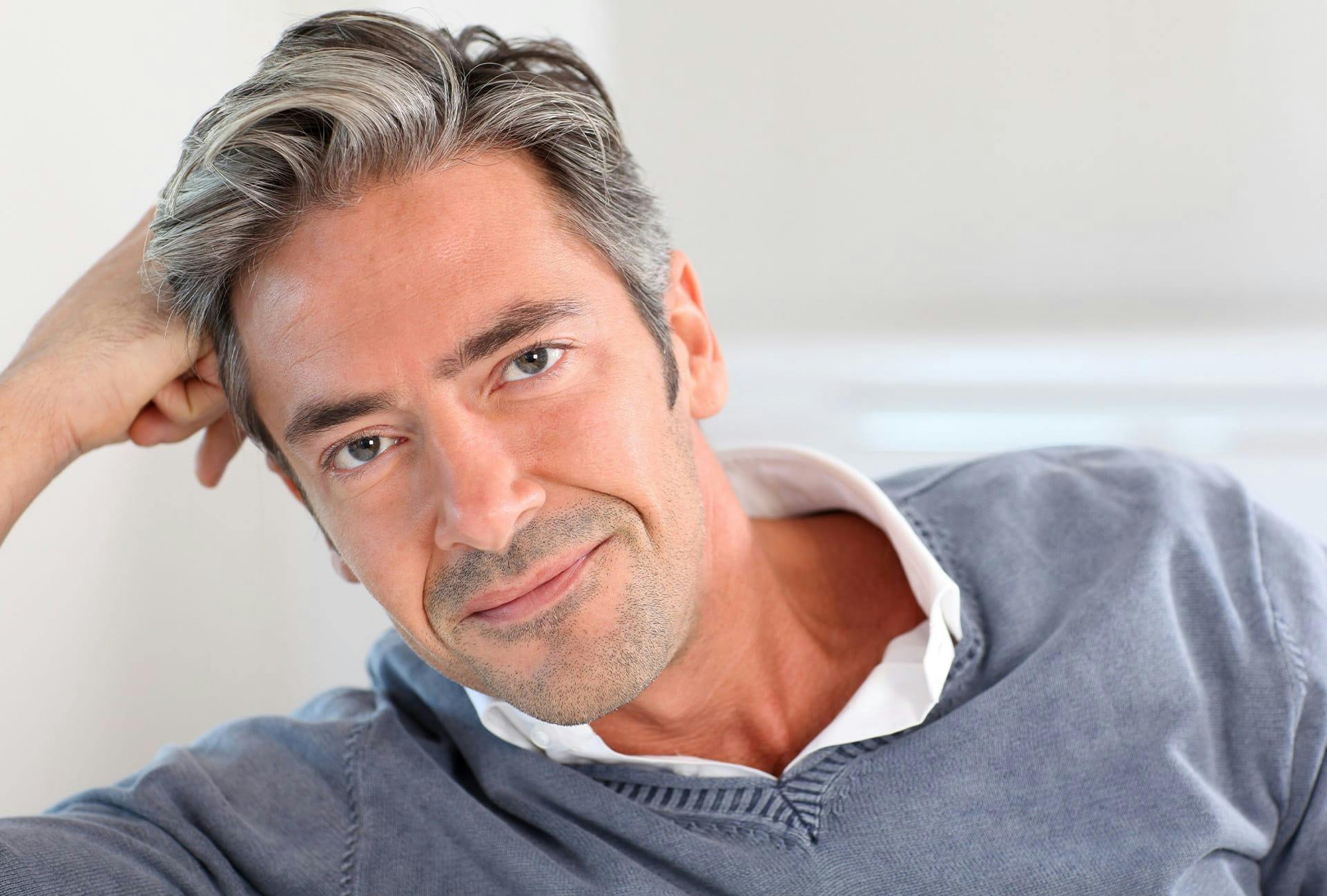man in grey sweater leaning on right arm
