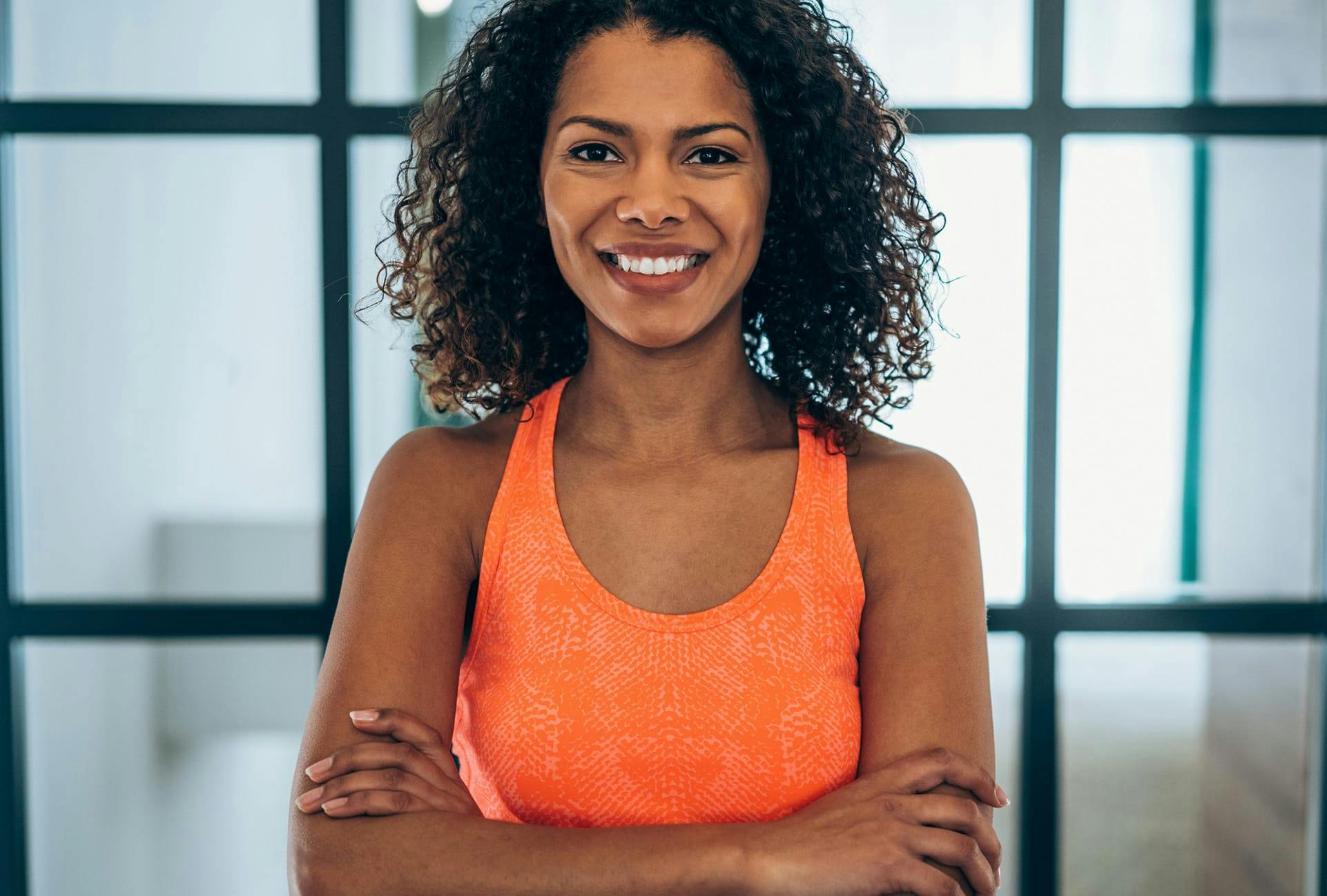 smiling woman with curly hair crossing her arms