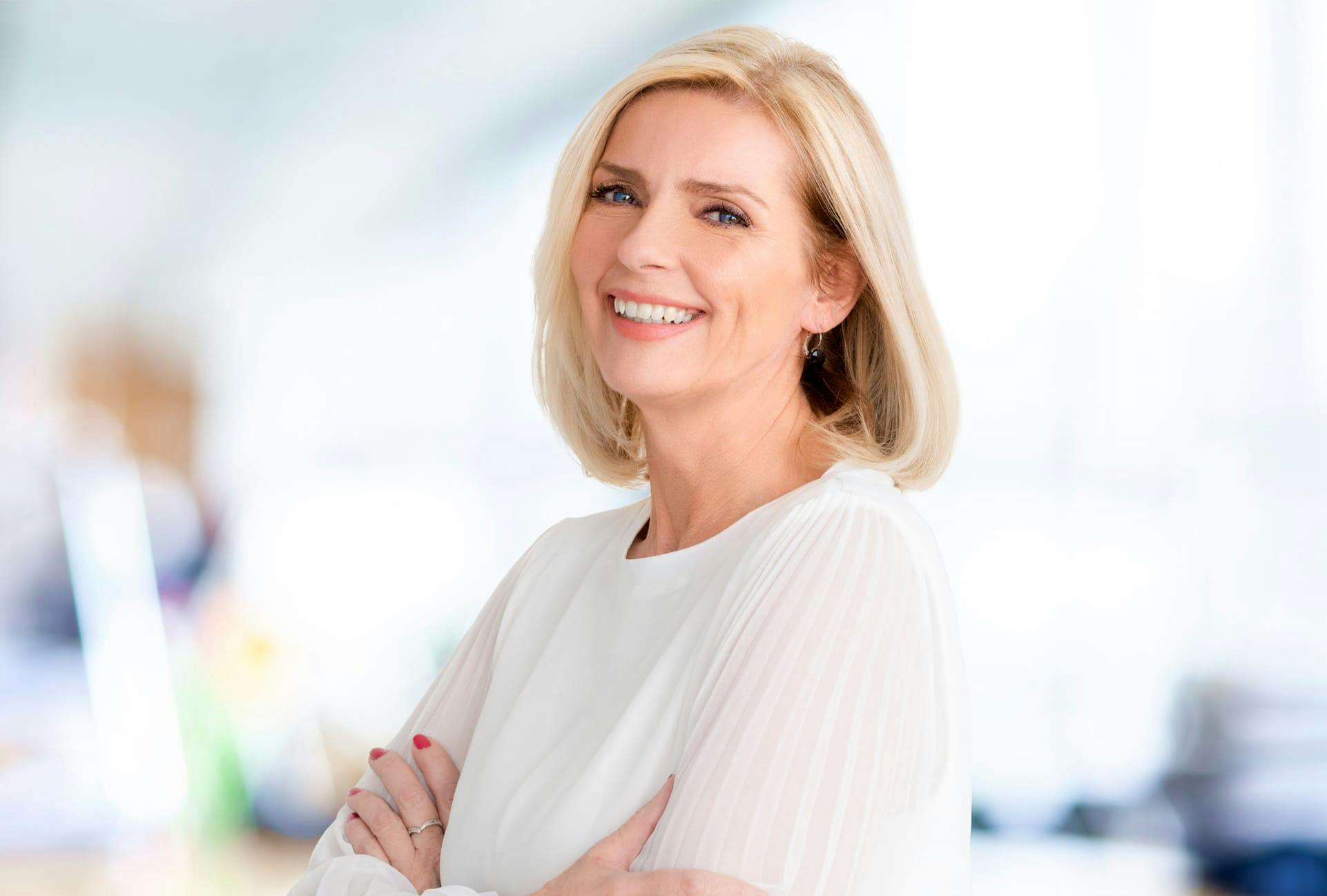blond woman with white blouse and red nails smiling at camera