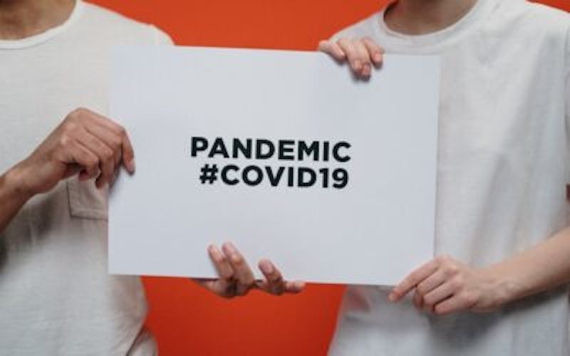 two people holding a sign that says pandemic covid19