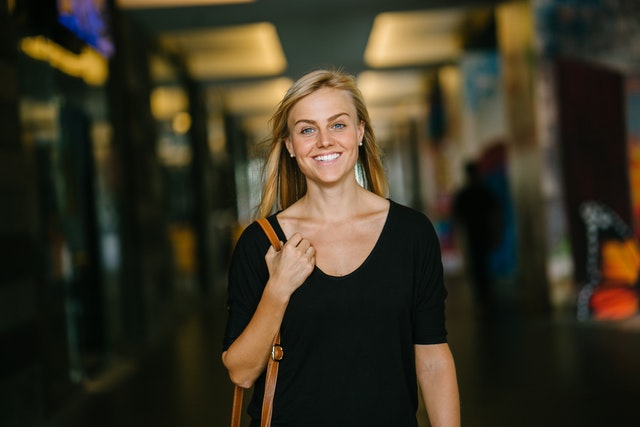 Woman wearing black smiling and walking down hallway