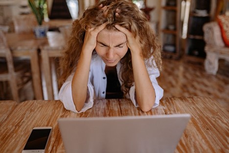 Woman with head in her hands sitting in front of laptop