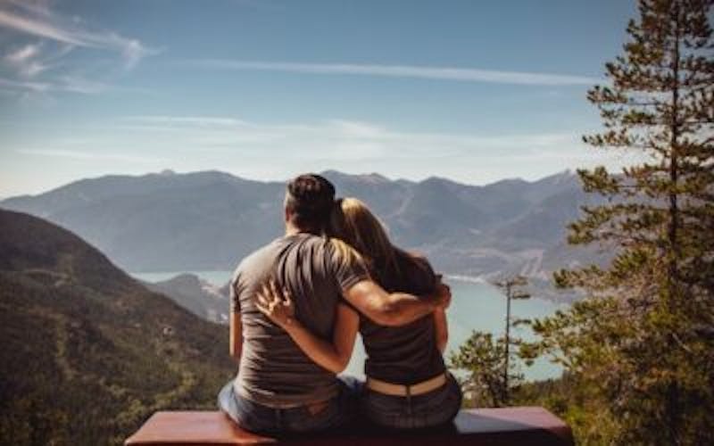 Couple sitting on a bench looking at the mountains