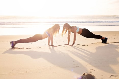 Two women doing pushups on the beach