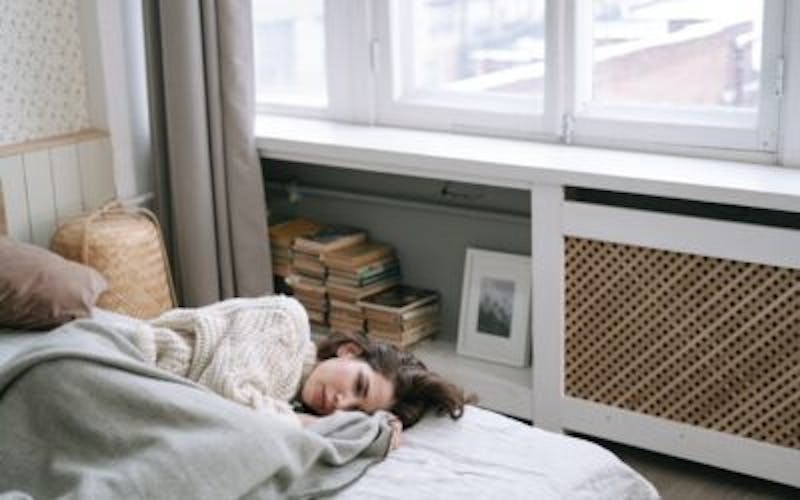 woman laying in bed with a blanket on it