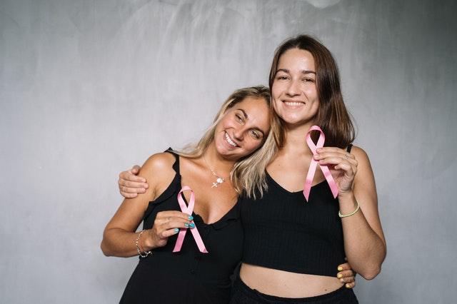 two women holding pink ribbons