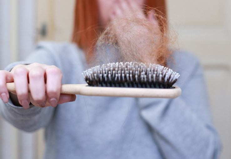 woman holding out brush full of hair