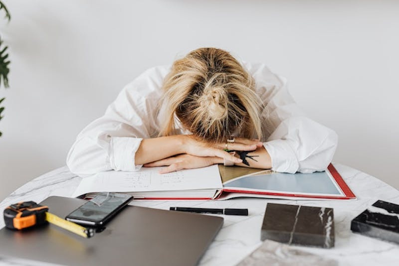 woman sitting at a table with her head on her hands