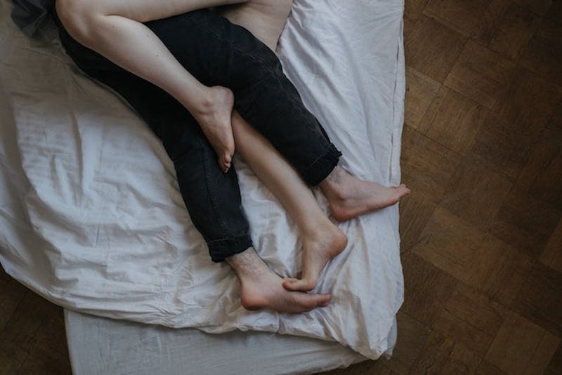 Two people laying on a bed with legs crossed