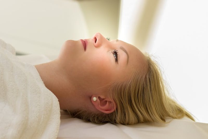 blond woman laying on a bed with a white towel