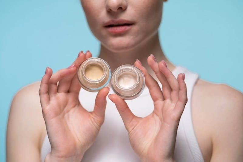 woman holding two jars of cream in both hands