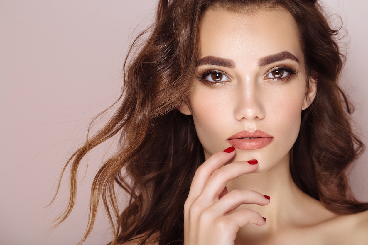 Woman with gorgeous lips stares at camer seductively with her fingers by her lips to emulate what potential results you could get with LipLase in Thousand Oaks