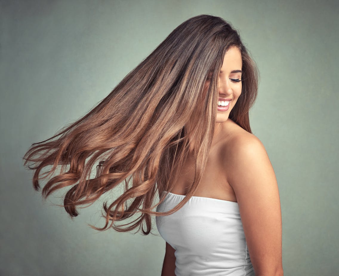 Woman happy swaying her Beautiful thick Hair enhanced by non invasive fotona er: yag sessions