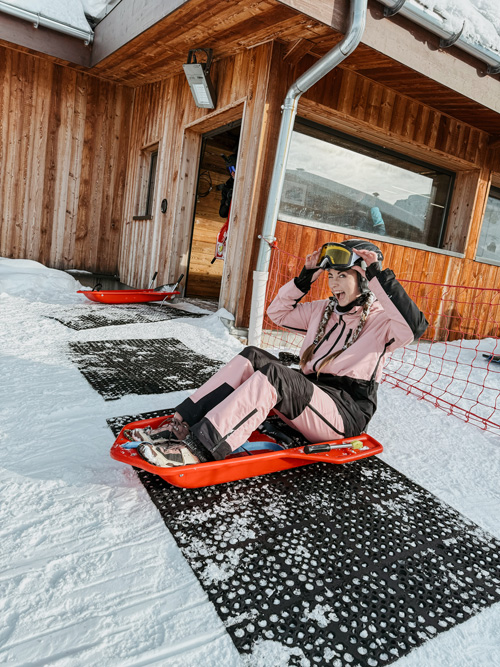 Personne assise sur une luge au sommet d’une piste enneigée à Courchevel, prête à descendre.