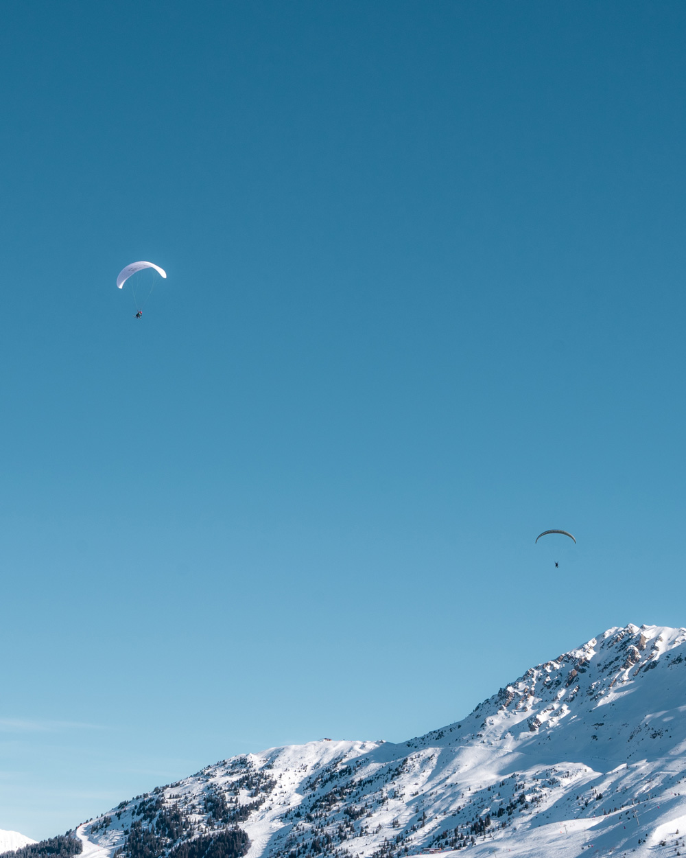 Two paragliders in the air at Col de la Loze in Courchevel