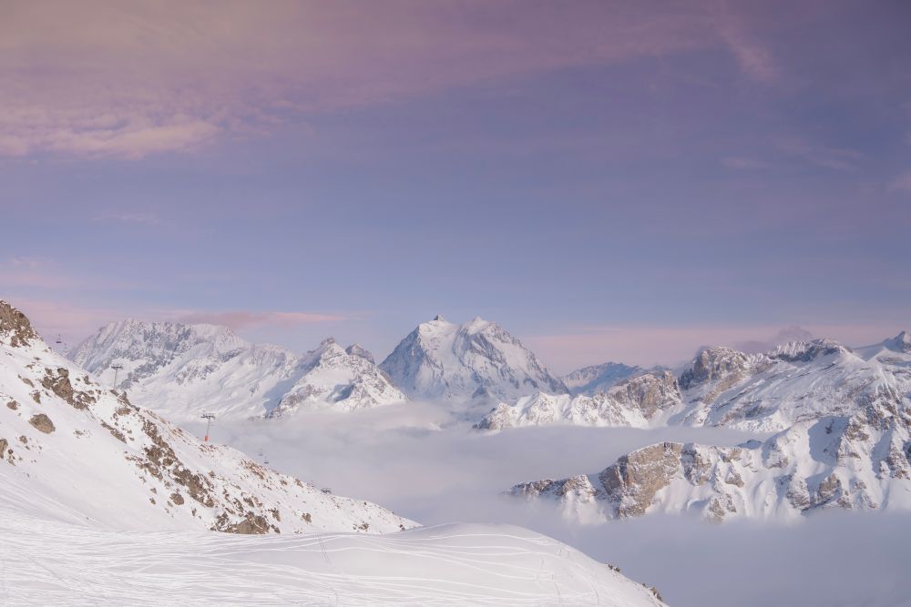 Panorama de sommets enneigés au-dessus d’une mer de nuages.