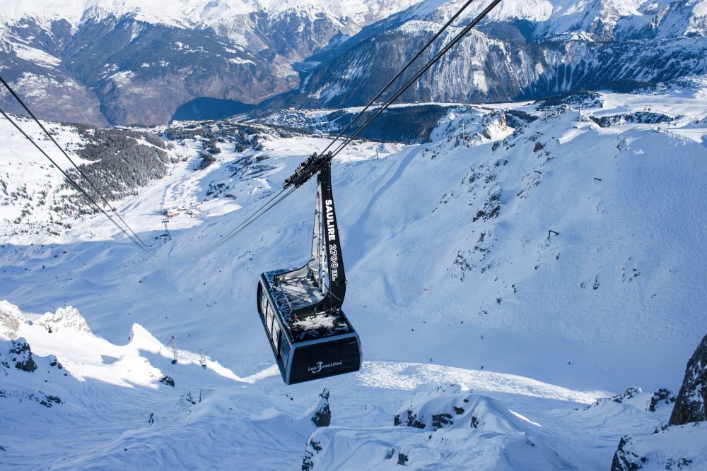 Téléphérique au-dessus d'une piste enneigée, entouré de montagnes