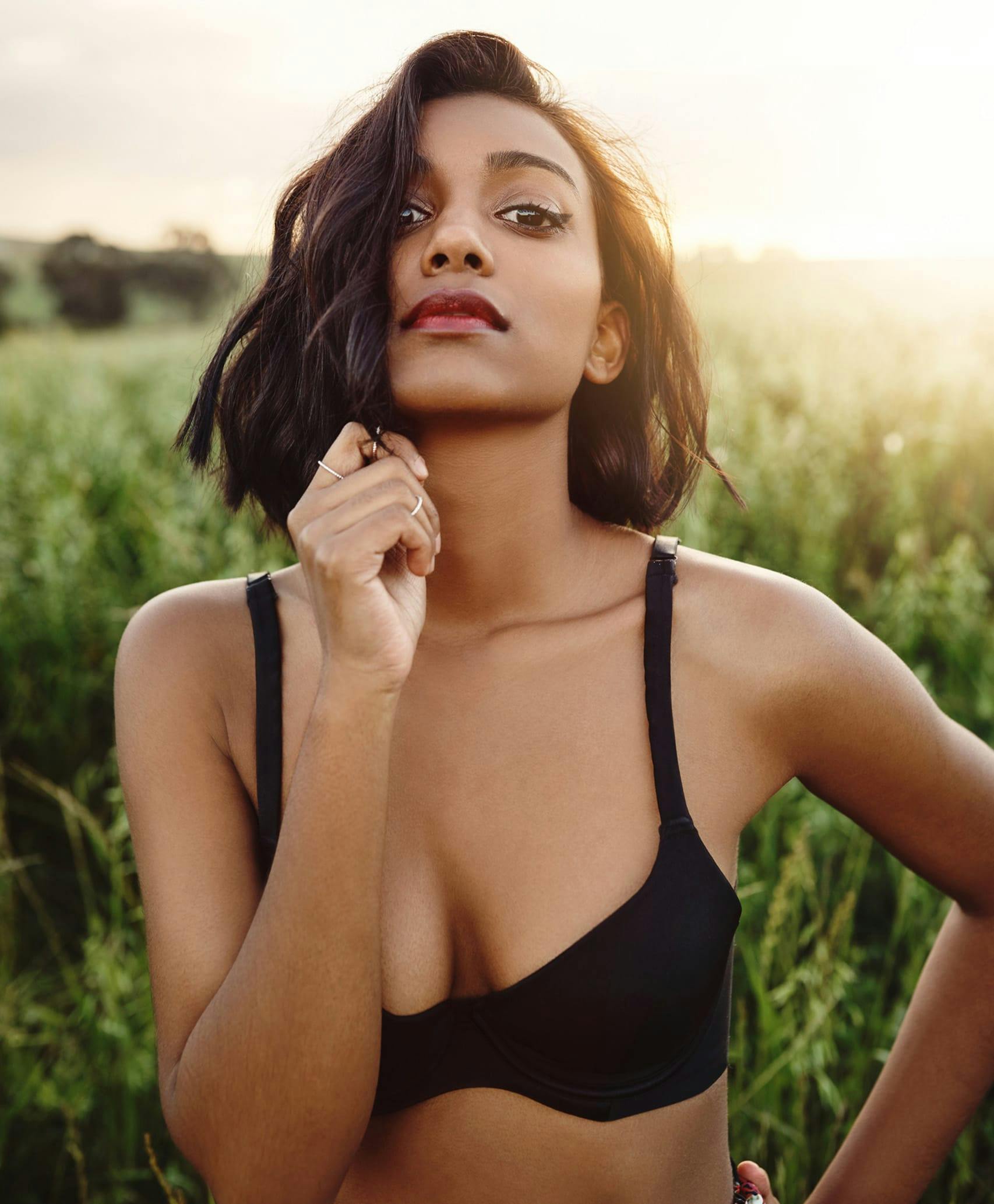 Woman posing in her bra in a green field.