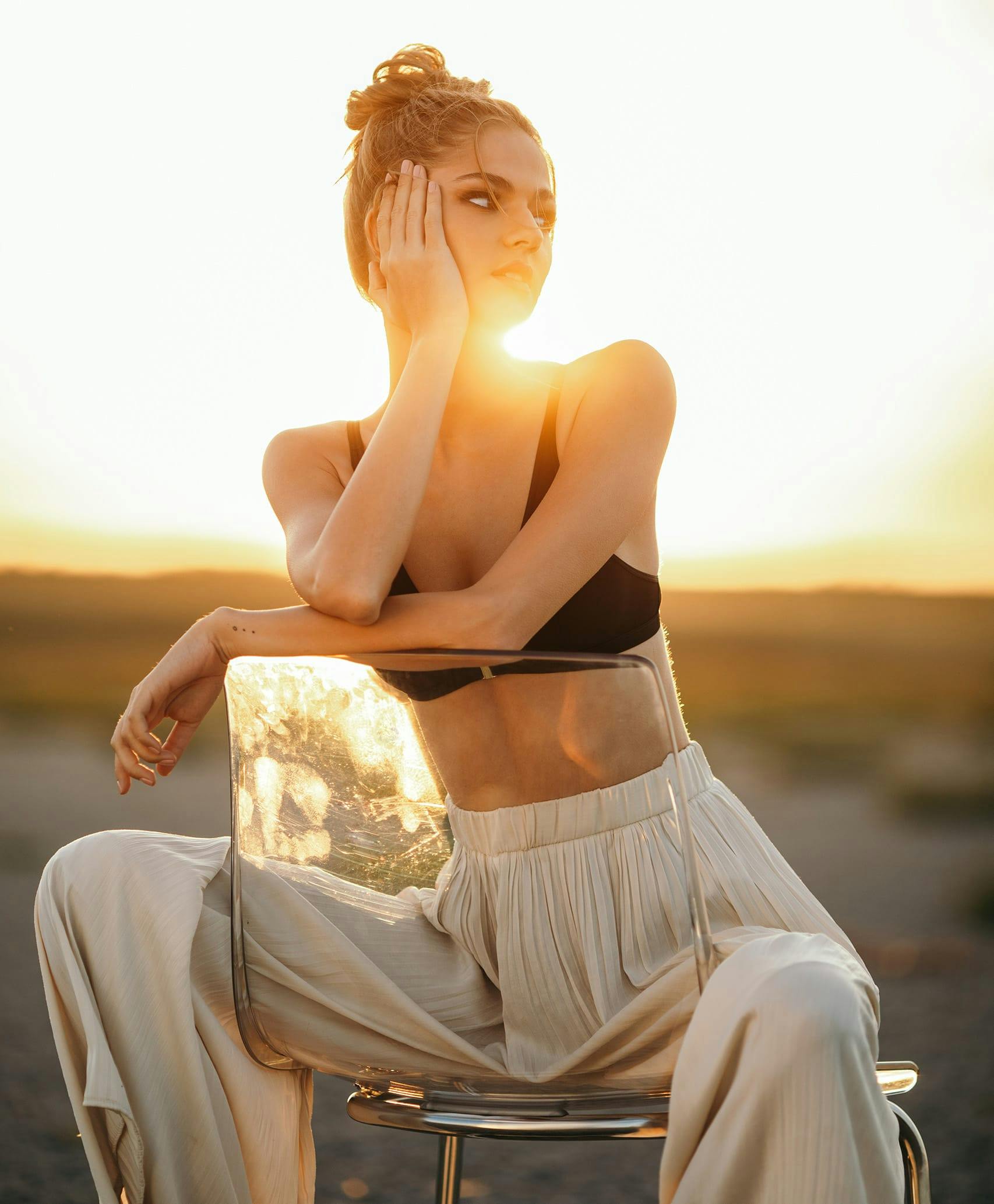 Woman in linen pants and swim top sitting backwards in a chair.