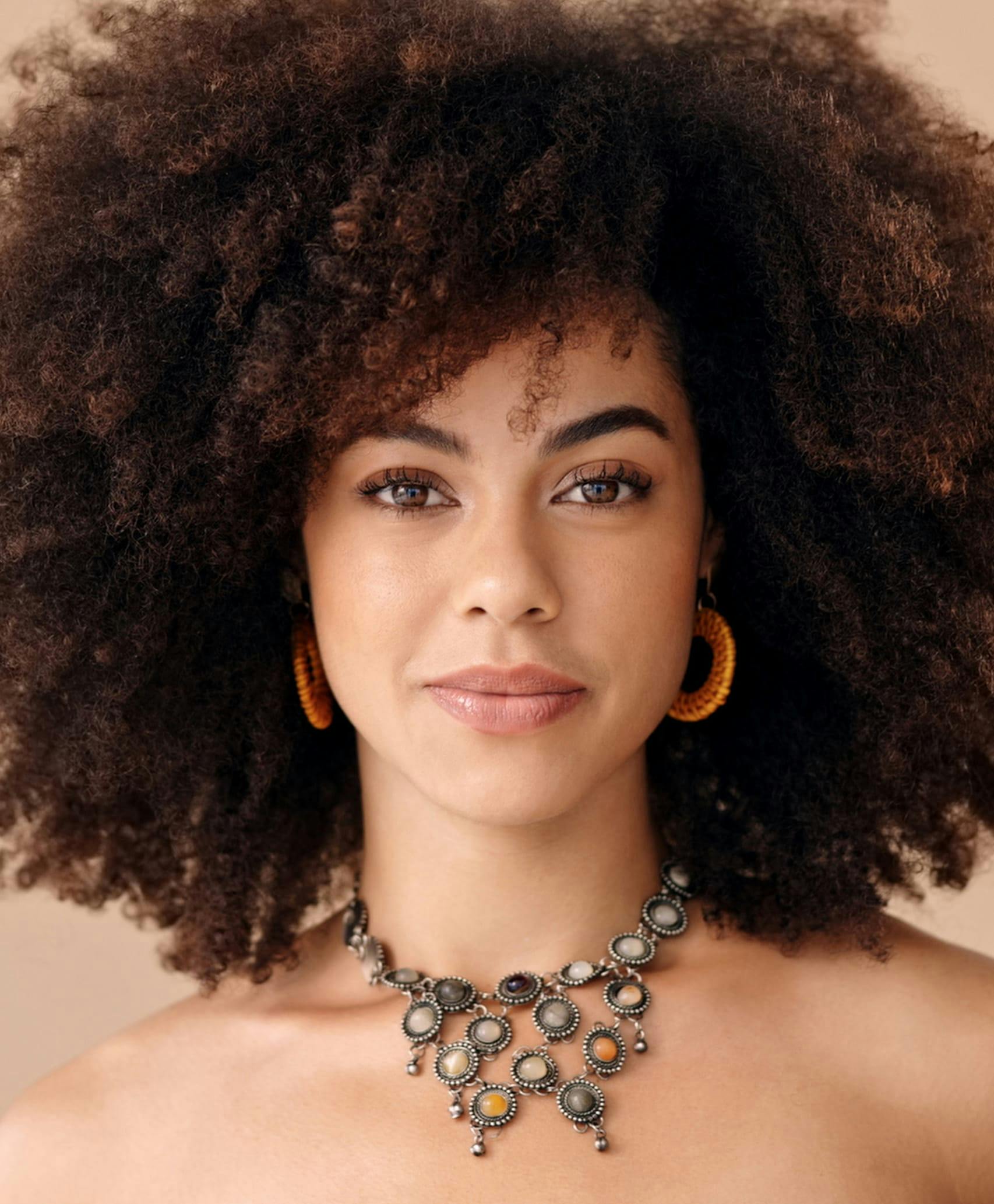 Smiling woman with frizzy hair and an elaborate necklace.