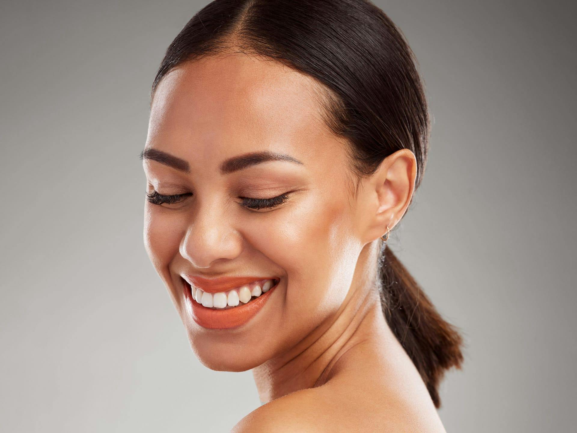 Smiling woman with her hair back looking down to her left.