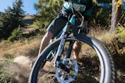 Aufnahme von vorne, unten: Ein Mann auf einem Mountainbike, er stellt den Lenker quer, man sieht die Bremsbeläge.