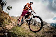 Ein Mann auf einem Mountainbike, im Hintergrund sieht man Berge.