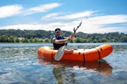 Ein Mann auf einem Packraft auf einem See.