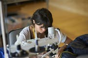A woman at a sewing machine, she is repairing a sleeping bag.