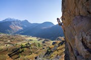 A woman is climbing a rock outside.