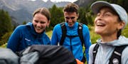 Drei Menschen lachen zusammen beim Wandern.
