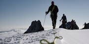 Personen auf einer Hochtour, sie gehen in einer Seilschaft über den Schnee.